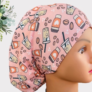 May include: A pink scrub hat with a pattern of iced coffee cups and coffee beans. The hat is made of a soft, comfortable fabric and is perfect for nurses, doctors, and other healthcare professionals.