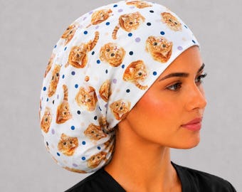 May include: A white scrub cap featuring a repeating pattern of orange tabby cat faces interspersed with small dark blue and light purple polka dots. The fabric head covering has a rounded, gathered shape designed to fit securely over the hair.
