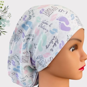 May include: White scrub hat with a colorful pattern of footprints and the text "Labor & Delivery" repeated throughout.