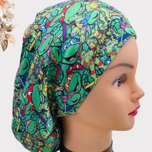 May include: Green, red, and black scrub hat with a Teenage Mutant Ninja Turtles print. The hat is made of a soft, comfortable fabric and is perfect for nurses, doctors, and other healthcare professionals.