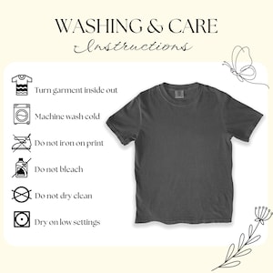 Puede incluir: Una camiseta gris oscuro de manga corta, exhibida sobre un fondo beige claro. La imagen incluye instrucciones de lavado: dar la vuelta a la prenda, lavar a m&aacute;quina en fr&iacute;o, no planchar sobre el estampado, no usar lej&iacute;a, no limpiar en seco y secar a baja temperatura.
