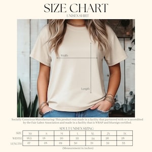 Puede incluir: Una camiseta unisex beige con una tabla de tallas. La tabla muestra medidas en pulgadas para el ancho y el largo, que van desde la XS hasta la 3X. El texto "SIZE CHART" y "UNISEX SHIRT" est&aacute;n en la parte superior. La camiseta la lleva una persona.