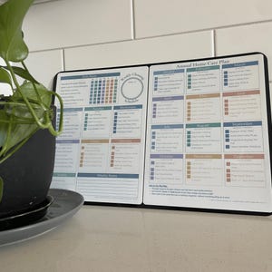 May include: A black and white home care planner with a weekly and monthly schedule. The planner includes sections for daily, weekly, and monthly tasks. The text on the planner includes the words "Weekly Cleaning Schedule" and "Annual Home Care Plan".