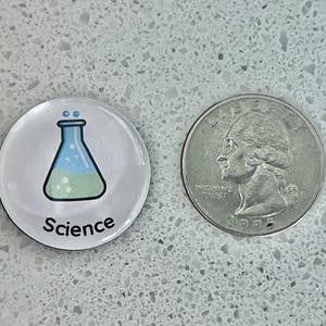 May include: A round, clear button with a science theme. The button features a cartoon illustration of a flask with blue and green liquid, and the word "Science" in black text. A U.S. quarter is next to the button.
