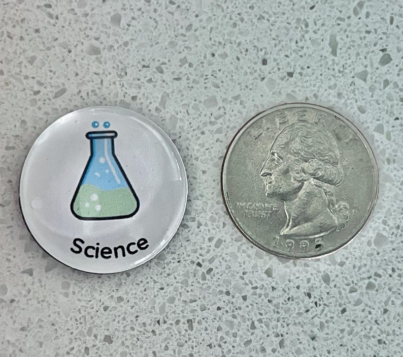 May include: A round, clear button with a science theme. The button features a cartoon illustration of a flask with blue and green liquid, and the word "Science" in black text. A U.S. quarter is next to the button.