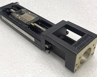 May include: A black and silver linear motion component with a rectangular frame and a cylindrical opening. The component has a label with the text "A9A0420" and "MADE IN JAPAN". The product is labeled "THK KR20".