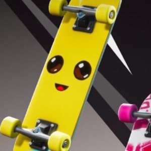 Pu&ograve; includere: Uno skateboard giallo con un viso di cartone animato e il testo "NANA NANA" sul fondo. Lo skateboard ha truck neri e ruote gialle.