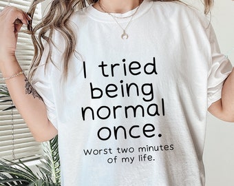 Op de afbeelding: Wit T-shirt met zwarte tekst die luidt: "Ik heb geprobeerd normaal te zijn. De slechtste twee minuten van mijn leven."