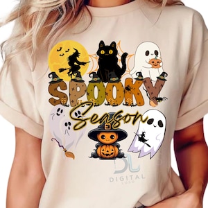 以下が含まれることがあります： ハロウィーンをテーマにしたグラフィックが特徴のベージュのTシャツ。「Spooky Season」の文字と、黒猫、幽霊、魔女、帽子をかぶったカボチャのデザイン。文字はハロウィーンの要素で装飾されています。