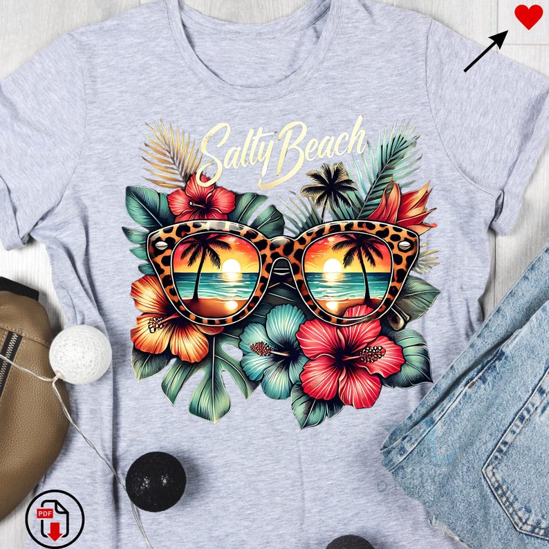 May include: A gray t-shirt with a graphic design of sunglasses with a sunset reflection, tropical leaves, and flowers. The text "Salty Beach" is printed on the shirt.