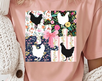 Könnte beinhalten: Ein pinkfarbenes T-Shirt mit einem Grafikdruck eines Puzzles aus vier Teilen. Jedes Teil zeigt ein anderes Blumenmuster und eine Silhouette eines Huhns. Die Puzzleteile sind in quadratischer Form angeordnet.