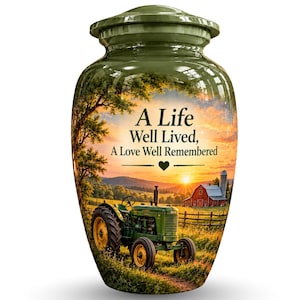 May include: A glossy olive green cremation urn featuring a printed landscape scene of a green tractor in a field at sunset with a red barn and silo. The text "A Life Well Lived, A Love Well Remembered" is printed in black above the tractor image.