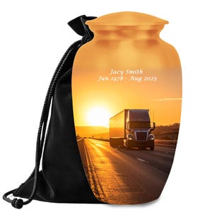 Peut inclure: Urne dorée avec une scène de coucher de soleil représentant un camion sur une autoroute. L'urne a un couvercle et est accompagnée d'un sac noir à cordon. Le texte sur l'urne indique "Jacy Smith Jun 1978 - Aug 2023."