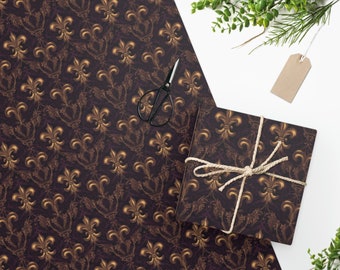 Puede incluir: Un rollo de papel de regalo y una caja de regalo envuelta con un patrón de flor de lis en dorado y marrón. La caja de regalo está atada con hilo. También hay unas tijeras negras y una etiqueta en blanco.