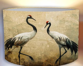 May include: A lampshade with a beige background and a vintage-style design featuring two red-crowned cranes. The cranes are facing each other, with one crane on the left side of the image and the other on the right side.