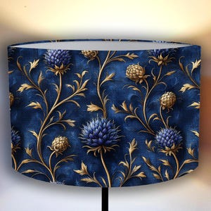 May include: A blue and gold lampshade with a floral pattern. The pattern features blue flowers with gold stems and leaves.