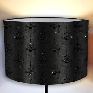 May include: Black lampshade with a repeating pattern of black glitter chandeliers on a black background.