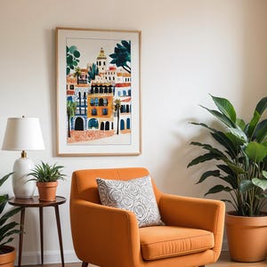 May include: A framed print of a colourful illustration of a cityscape with buildings and palm trees. The print is hanging on a white wall above an orange armchair with a patterned cushion. There are two potted plants in the room.