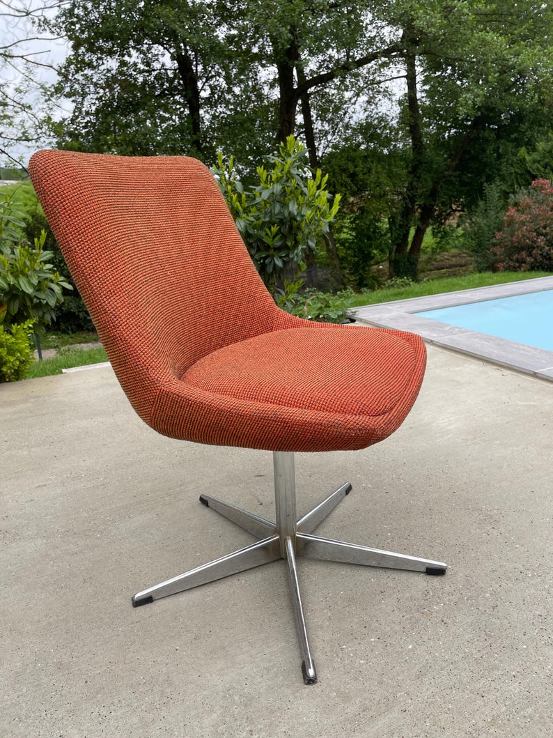 Peut inclure: Une chaise pivotante avec un si&egrave;ge en tissu rouge orang&eacute; et une base chrom&eacute;e &agrave; cinq branches.