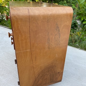 May include: A wooden dresser with rounded edges and five drawers. The dresser is made of light brown wood with a natural finish.