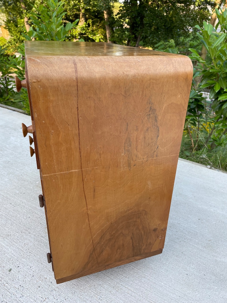 May include: A wooden dresser with rounded edges and five drawers. The dresser is made of light brown wood with a natural finish.