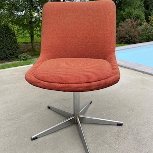 Peut inclure: Une chaise pivotante avec une base en &eacute;toile et un rev&ecirc;tement en tissu orange.