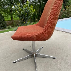 Peut inclure: Une chaise pivotante avec une base en &eacute;toile et un rev&ecirc;tement en tissu orange. La chaise est en m&eacute;tal et a un design moderne.