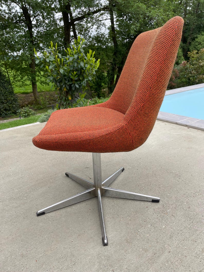Peut inclure: Une chaise pivotante avec une base en &eacute;toile et un rev&ecirc;tement en tissu orange. La chaise est en m&eacute;tal et a un design moderne.