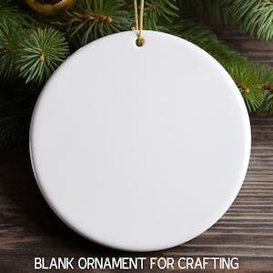 May include: A white ceramic round ornament with a gold string attached. The ornament is blank and ready for crafting.