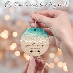 May include: Round ceramic ornament with a beach scene and the text "girls trip Cabo San Lucas 2024" with two wine glass icons.