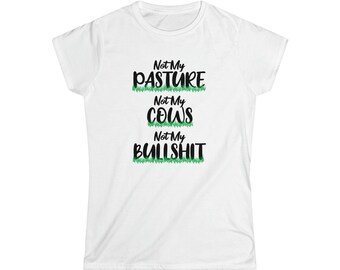 May include: White t-shirt with the text "Not My Pasture, Not My Cows, Not My Bullshit" in black and green lettering. The words are stacked vertically with a green grass design between each line. The shirt has short sleeves and a crew neck.