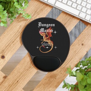 以下が含まれることがあります： 黒色のマウスパッドで、金色のドラゴン柄と「Dungeon Master」と「Mom」の文字が書かれています。