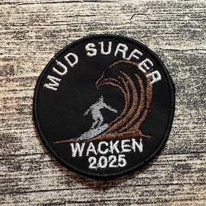 Puede incluir: Parche circular negro con texto bordado blanco «MUD SURFER» y «WACKEN 2025». El parche presenta un surfista surfeando una ola marrón. Ideal para ropa.