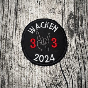 Könnte beinhalten: Ein schwarzer, runder Aufnäher mit dem Wort "WACKEN" in Weiß, das oben gewölbt ist. Darunter eine Handgeste mit erhobenem Zeige- und kleinem Finger und die roten Zahlen "3" auf beiden Seiten. Das Jahr "2024" steht unten.