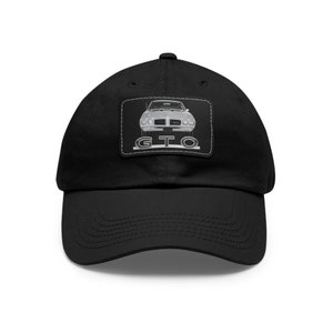 May include: A black baseball cap with a white and gray patch featuring a vintage silver Pontiac GTO muscle car with the text "GTO" in a black outline.