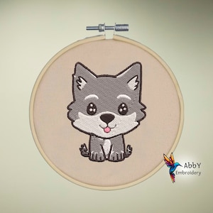 Könnte beinhalten: Stickerei-Hoop-Kunst mit einem niedlichen Cartoon-Grauwolf mit weißen Akzenten und einer rosa Zunge. Der Wolf sitzt auf einem beigefarbenen Stoffhintergrund.