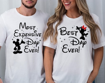 May include: Two white t-shirts with black text and images. The first shirt says "Most Expensive Day Ever!" and features a black silhouette of Mickey Mouse. The second shirt says "Best Day Ever!" and features a black silhouette of Minnie Mouse with a red bow.
