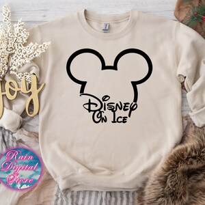 May include: A beige sweatshirt with a black Mickey Mouse head and the text "Disney On Ice" printed on the front.