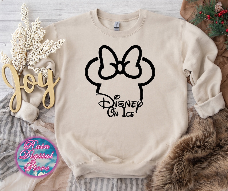 May include: A beige sweatshirt with a black outline of Mickey Mouse's head with a bow and the text "Disney On Ice" underneath.