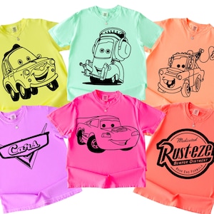 May include: A collection of colorful t-shirts featuring cartoon car designs. The shirts are in various colors, including yellow, mint green, orange, pink, and purple. Each shirt has a different car character or logo printed in black.