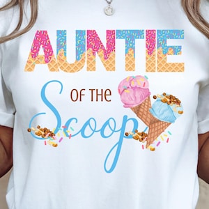 Può includere: T-shirt bianca con la scritta "AUNTIE of the Scoop" in lettere colorate. La parola "AUNTIE" è in rosa e blu con un motivo a cialda. La parola "Scoop" è in un carattere blu chiaro, con grafiche di coni gelato.