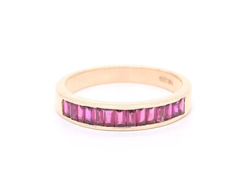 May include: A gold band ring with a row of pink baguette-shaped gemstones.