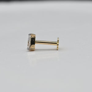 May include: A gold nose stud with a clear gemstone.
