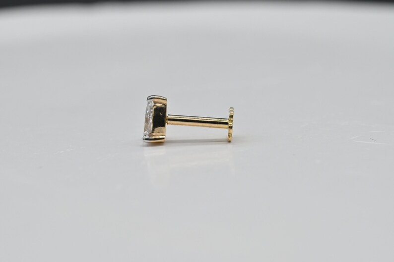 May include: A gold nose stud with a clear gemstone.