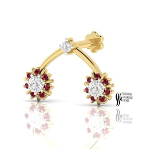 Op de afbeelding: Een gouden neusring met een gebogen ontwerp en twee bloemvormige accenten. Elke bloem heeft een ronde witte edelsteen omringd door kleinere rode edelstenen.
