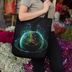 May include: A black tote bag with a colorful abstract design of a sphere with glowing lines. The sphere is surrounded by a dark ring. The bag is being held by a person.