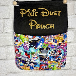 May include: A black fabric wall pouch featuring the gold glitter text Pixie Dust Pouch. The lower section displays a colorful pattern of cartoon characters including mice and ducks on a cruise ship, with a wooden dowel and black cord for hanging.