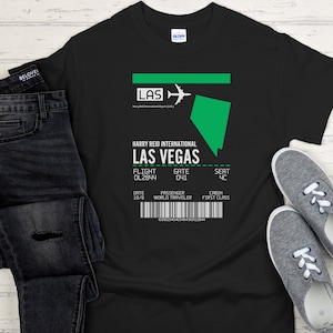 Puede incluir: Camiseta negra con un gráfico blanco de una tarjeta de embarque para el Aeropuerto Internacional Harry Reid en Las Vegas. El gráfico incluye el código del aeropuerto LAS, el número de vuelo DL2844, la puerta 041, el asiento 4C, la fecha 10/6, el pasajero World Traveler y la cabina First Class.