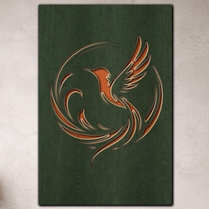 Op de afbeelding: Houten wandkunst met een kolibrie-ontwerp. Het kunstwerk toont een kolibrie in oranje- en bruintinten tegen een donkergroene achtergrond. De vogel is omcirkeld door een decoratief wervelpatroon.