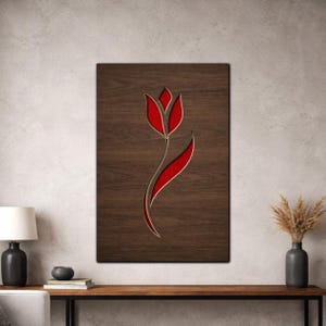 May include: Wooden wall art featuring a red tulip design. The tulip is carved into a dark brown wooden panel, with a red interior. The artwork is rectangular and mounted on a light-colored wall. The tulip's stem curves gracefully.